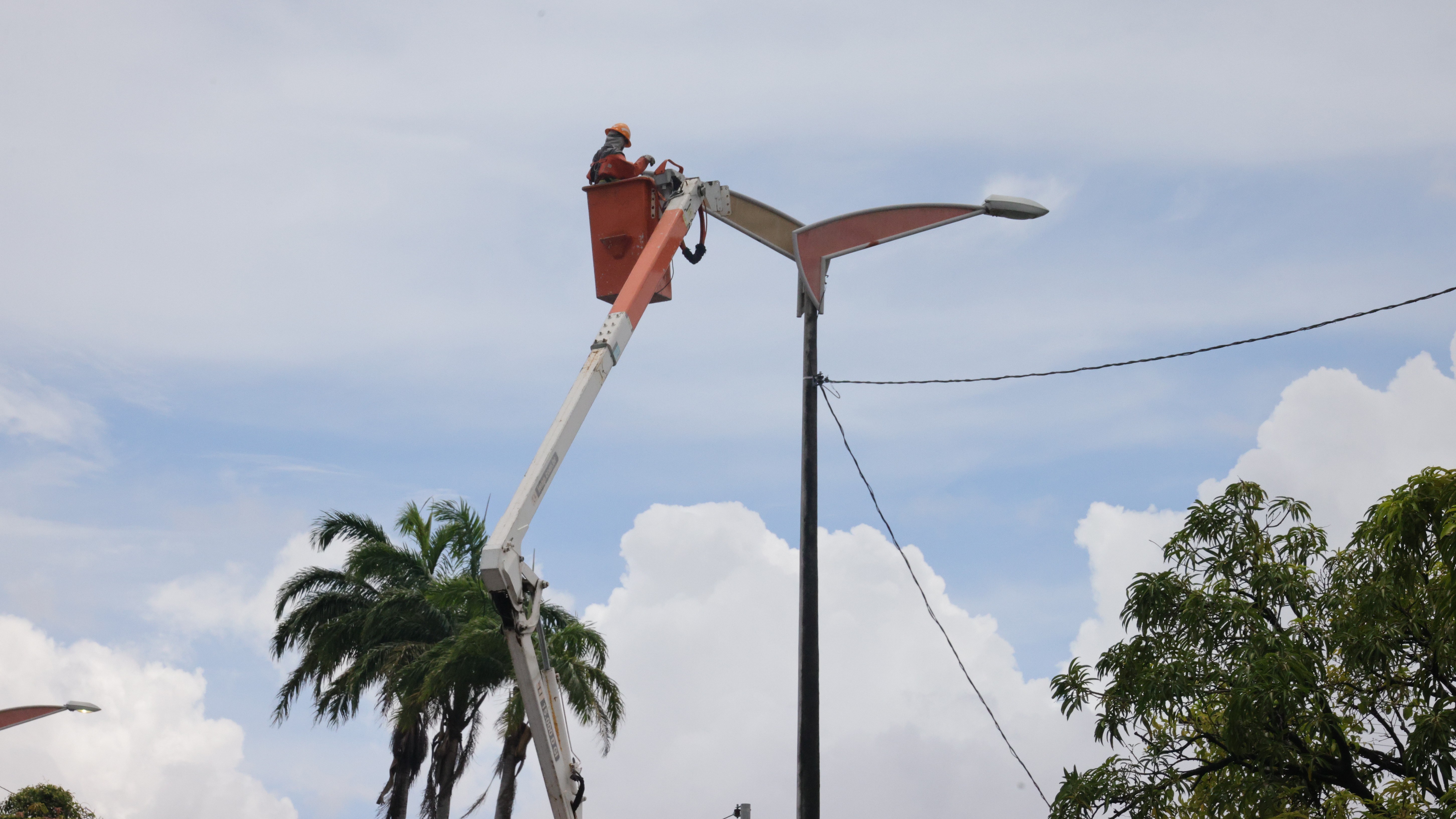 homens trocando lâmpadas numa avenida